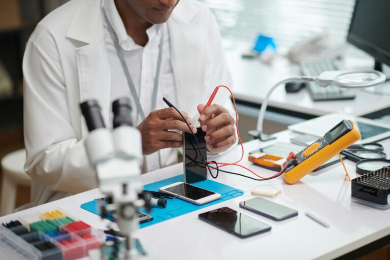 Technicien vérifiant la batterie d'un smartphone, illustrant les services de réparation de batteries chez Teclab.